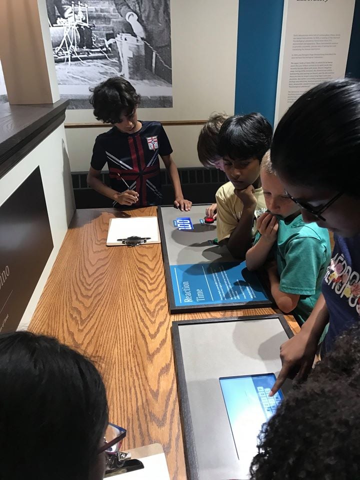 Young students gathered around an exhibit